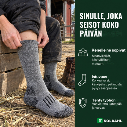 Nainen vetää harmaata työsukkaa jalkaan tallin pihalla, sinulle, joka seisot koko päivän