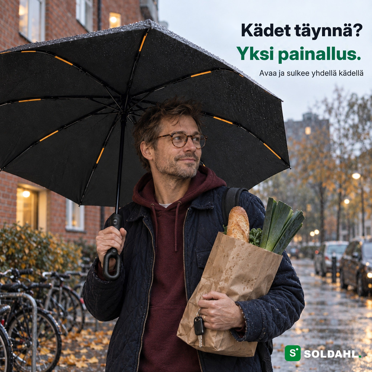 Mies ostoskassin kanssa pitää Myrskysateenvarjoa rengaskahvasta yhdellä kädellä sateessa
